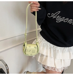 Detail of light green PU leather saddle bag with cartoon bear illustration and adjustable strap