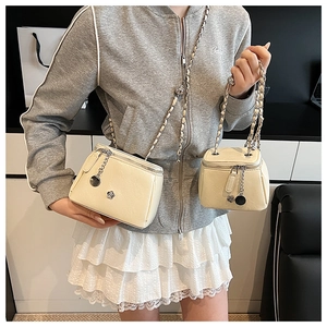 Photo lifestyle d'un mannequin portant des mini sacs à chaîne blanc crème avec breloques