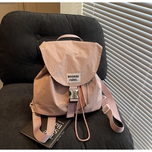 Detail of dusty pink nylon drawstring backpack with buckle flap and woven label