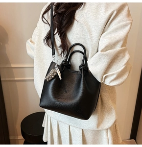 Close-up of black litchi pattern leather handbag with silver metallic bead charm accessory