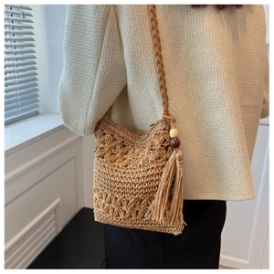 Detail of hollow straw woven bag with fringe tassels and wood bead decorations