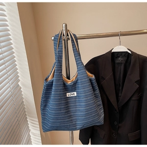 Close-up of blue striped tote bag featuring a stitched LOVE label and canvas texture