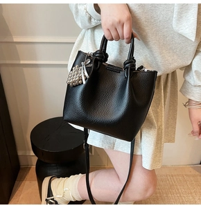 Detail of black pebbled leather mini tote with silver bead charm and knotted handles