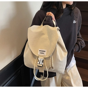 Detail of beige canvas drawstring backpack with large flap and metal buckle closure
