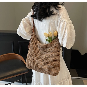 Detail of hand-woven straw hobo bag with brown leather strap and textured surface
