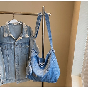 Blue denim tote bag with adjustable strap and small round pouch hanging on a rack