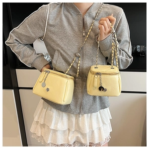 Détail de sacs vanity jaunes en cuir grainé avec bandoulière chaîne et breloque fleurie