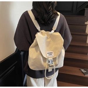 Close-up of cream canvas drawstring backpack with metal buckle and waswac rules tag