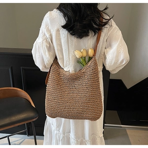 Detail showing textured brown straw tote bag with premium leather shoulder strap