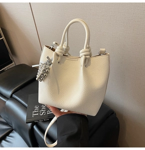 Litchi texture leather bucket bag in cream white with knot handles and bead charm