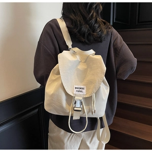 Detail view of cream drawstring backpack showing flap design and silver metal buckle