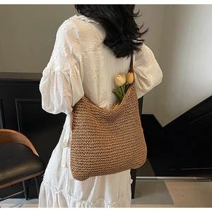 Detail of hand-woven straw tote bag with brown leather strap and floral interior