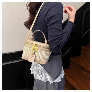 Model wearing a beige woven box bag with leather trim and golden hardware detailing