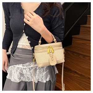 Model wearing a vintage straw cylinder bag with leather trim and gold double zippers