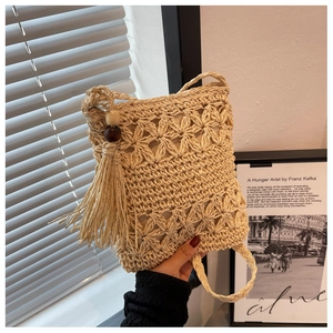 Detail of bohemian straw bag showing intricate crochet floral patterns and wood bead tassels