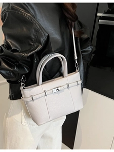 Borsa a tracolla grigio chiaro con motivo litchi e fibbia argentata indossata da una modella