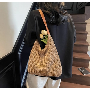 Detail of large woven straw tote bag with brown leather straps and spacious interior
