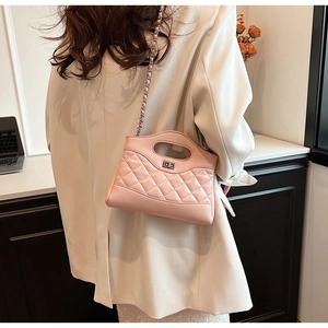 Lifestyle view of pink quilted handbag with silver chain strap worn by a model