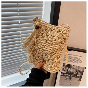 Close-up of hollow straw woven phone bag with tassel and wood beads for summer beach look
