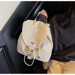 Detail of off-white drawstring bucket backpack with metal buckle and woven label