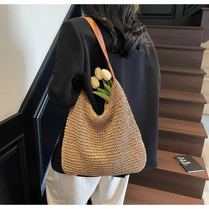 Close-up of woven straw tote bag featuring brown faux leather straps and floral accents
