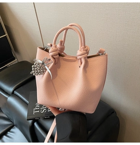 Close-up of pink litchi grain bucket bag with decorative silver beads and soft ribbon