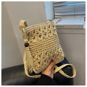 Détail d'un sac en paille tissé ajouré avec motifs floraux, longues franges et perles en bois