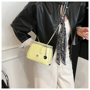 Detail of lime green mini crossbody bag with glossy finish and silver flower clasp