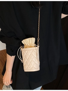 Chic beige quilted bucket bag with drawstring closure and golden chain strap