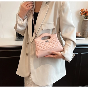 Detail of light pink quilted leather handbag with metal chain and turn-lock closure