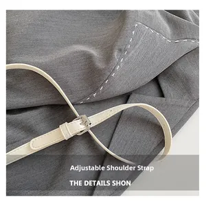 Macro detail of adjustable beige faux leather strap with silver buckle on grey fabric