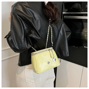 Detail of yellow leather chain bag featuring camellia metal logo and chain strap