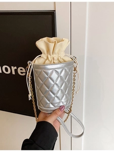 Silver quilted drawstring bucket bag with metallic chain strap and beige canvas lining