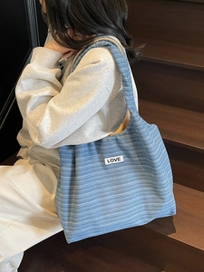 Blue striped canvas tote bag with LOVE patch shown in a stylish outdoor setting