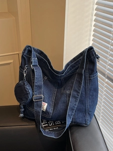 Large dark blue denim tote bag with round pouch and adjustable strap on black leather