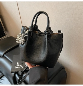 Close-up of black lychee texture bucket bag with knotted handle and silver bead charm