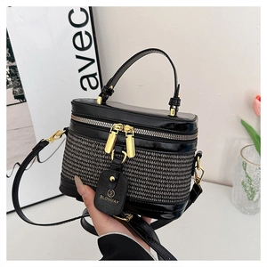 Close-up of box-style handbag featuring woven texture and gold zipper details