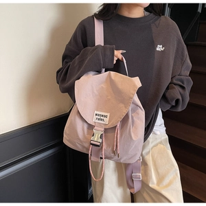 Close-up of a lilac drawstring backpack with buckle flap and label on a side-view model