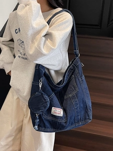 Large denim tote bag in dark blue with round coin purse shown on female model