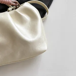 Detailed macro view of the creamy white pleated leather texture and soft woven handle