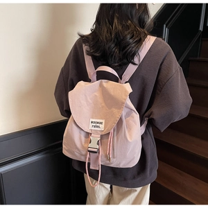 Detail of pink canvas drawstring backpack with silver buckle and woven brand label