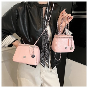 Détail du set de sacs bandoulière rose vif avec logo camélia et bandoulière chaîne
