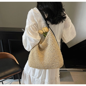 Detailed view of straw shoulder bag with black leather strap and decorative tulips