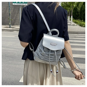 Silbergrauer Mini-Rucksack mit Faltendesign und Quasten-Kordelzug-Detail am Model getragen