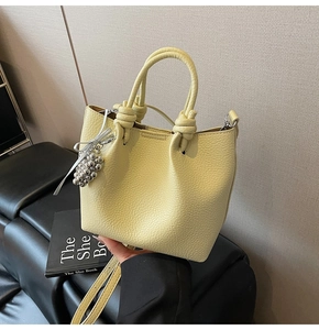 Detail of light yellow lychee pattern leather bucket bag with silver grape charm