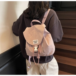 Detail of light pink nylon drawstring backpack with metal buckle and woven cord accents