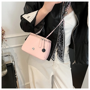 Détail du sac bandoulière rose en similicuir avec fleur en métal et double zip