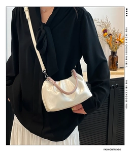 Detail of a pearl white pleated cloud bag with a pink woven handle and thin shoulder strap