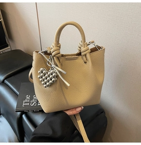 Detail of lychee pattern leather bucket bag with knotted handle and heart charm