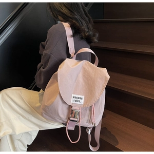 Detailed view of pink nylon bucket backpack showing silver buckle and side zipper